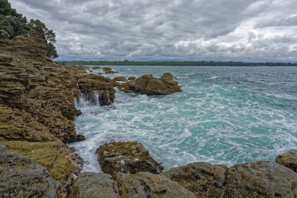 Tauranga, New Zealand - January 15, 2018:  Pacific ocean Waves hitting the rocks.