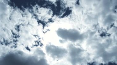 Parlak, mavi ve bulutlu gökyüzü güneş patlamaları ve zaman geçmesiyle aydınlanır..