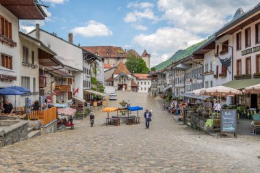 GRUYERES, SWITZERLAND - MAY 25, 2018: Rue de Bourg, the midieval road up to the Gruyeres Casltle. Nice restaurants and happy people. clipart
