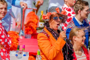 Schipluiden, Hollanda - 4 Ağustos 2017: Kadın turuncu uygun bir şekilde dekore edilmiş teknede şarkı. Güzel çiçek ve sebze ile dekore edilmiş muhteşem yıllık Westland kayan geçit Hollanda tekneler.