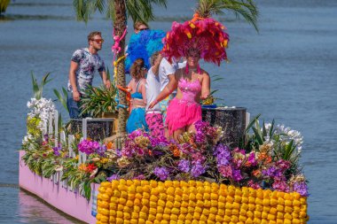 Schipluiden, Hollanda - 03 Ağustos 2018: Yıllık geçit töreni tekneler sebze ve çiçekler ile dekore edilmiştir. Güzel bir şekilde dekore edilmiş teknede kalabalığa sallayarak renkli dansçı kızları.