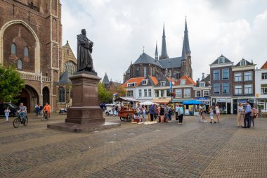 Turistler, öğrencilere bisiklet ve Delft, Hollanda'nın şehir merkezinde bir takunya satıcı ile kilisenin önünde kare büyük pazar.