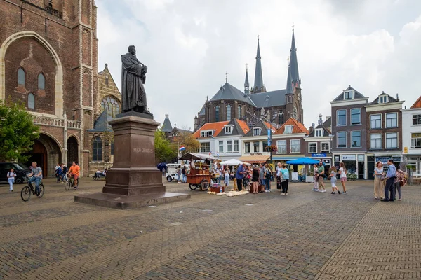 Turistler, öğrencilere bisiklet ve Delft, Hollanda'nın şehir merkezinde bir takunya satıcı ile kilisenin önünde kare büyük pazar.