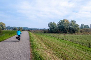 Kadın lezbiyen taşkın ovaları, Wageningen, Hollanda Nederrijn Nehri boyunca bir bisiklet üzerinde. Ren içinde yüksek su ile bu dike kadar sudur.