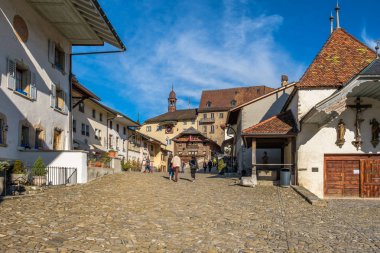 Rue de Bourg Gruyeres, Switzerland,  the medieval road up to the Gruyeres castle. Tourists on their way to visit the castle. clipart