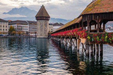Lucerne tarihi şehir sonbahar ışık ve ünlü ahşap Şapel Köprüsü kırmızı çiçekli görünümünü