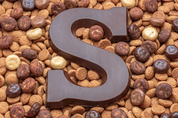 A chocolate letter S on a pile of dutch candy called Pepernoten, traditional sweets for the celebration of Saint Nicolas or Sinterklaas, a dutch holiday at 5 December