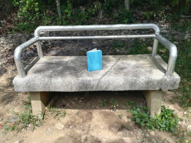 Mavi kapaklı kitap bankta yatıyor.