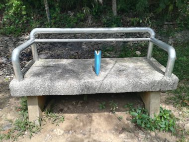 Mavi kapaklı kitap bankta yatıyor.