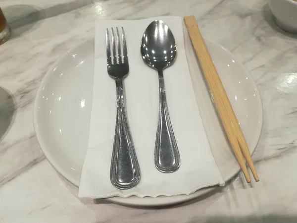 Masada boş beyaz tabak, çatal, kaşık ve çatal bıçak takımı