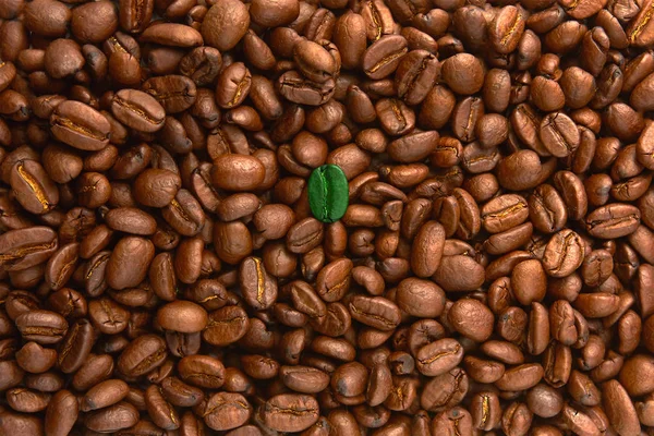 Green coffee beans among brown coffee