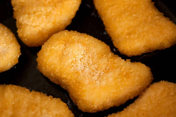 Dondurulmamış nuggets bir tavada. Buz ile bir nuggets.
