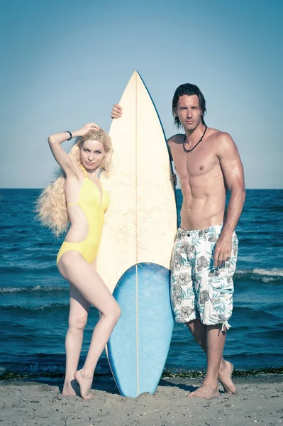 Pareja en la playa con tabla de surf . — Foto de Stock