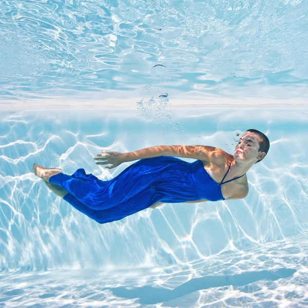 与蓝色的裙子在游泳池水下女人肖像 — 图库照片