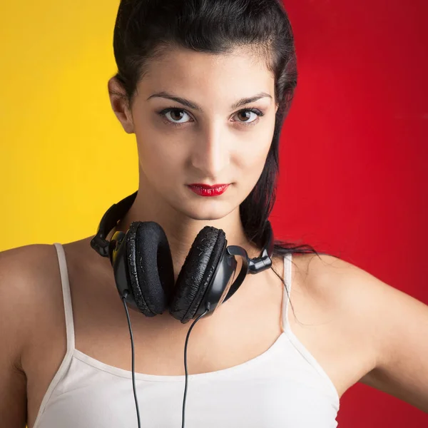 Beautiful girl listening to music against red and yellow backgro — Zdjęcie stockowe