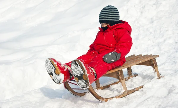 Kind rutscht mit Schlitten in den Schnee. — Stockfoto