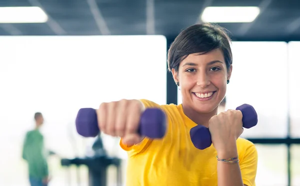 Jong meisje uitoefenen met halters in de sportschool. — Stockfoto