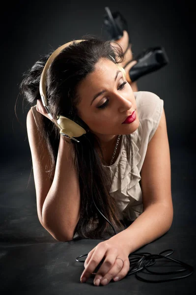 Mooi meisje luisteren naar muziek tegen donkere achtergrond. — Stockfoto