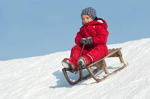 Kid posuvné s sáňkování na sněhu. — Stock fotografie