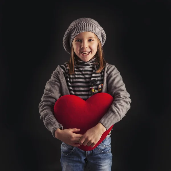 Young girl with red heart on black background. — Stockfoto