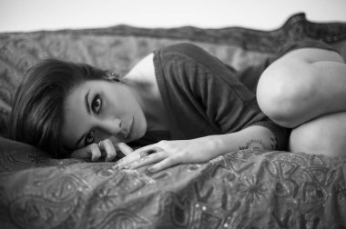 Sensual portrait of beautiful girl with tattoo lying on sofa. Bl