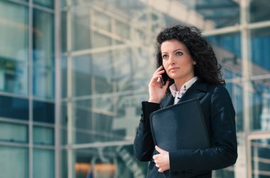 açık havada, modern binanın arka plan olarak telefonla konuşurken iş kadın portresi. 