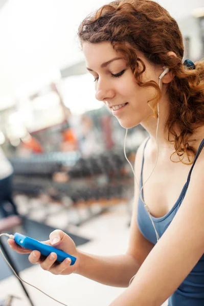 Retrato de mujer joven en el gimnasio mientras escucha música . — Foto de Stock