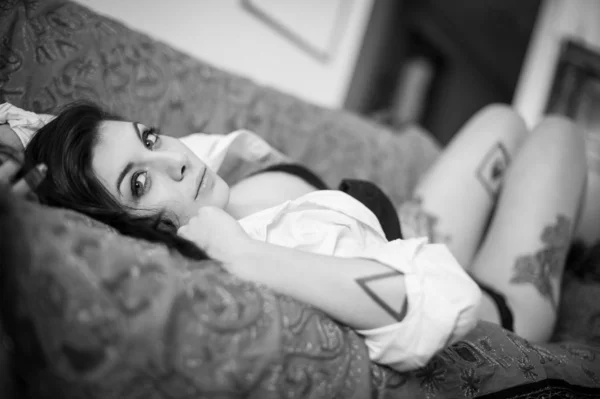 Sensual portrait of beautiful girl with tattoo lying on sofa. Bl — Stok fotoğraf