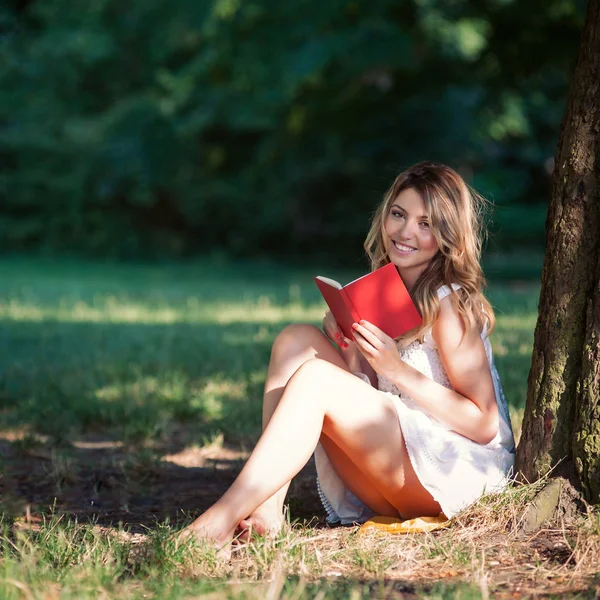 公園の木の下で本を読む美しい若い女性 — ストック写真