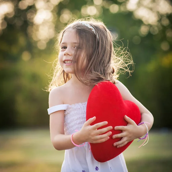 Menina doce com coração vermelho ao ar livre no parque . — Fotografia de Stock