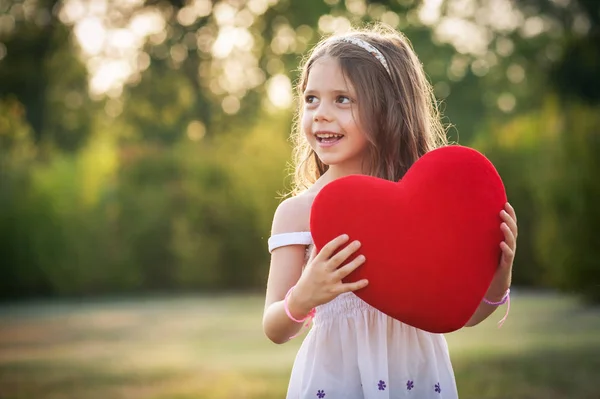 Lief meisje met rood hart buitenshuis in het Park. — Stockfoto