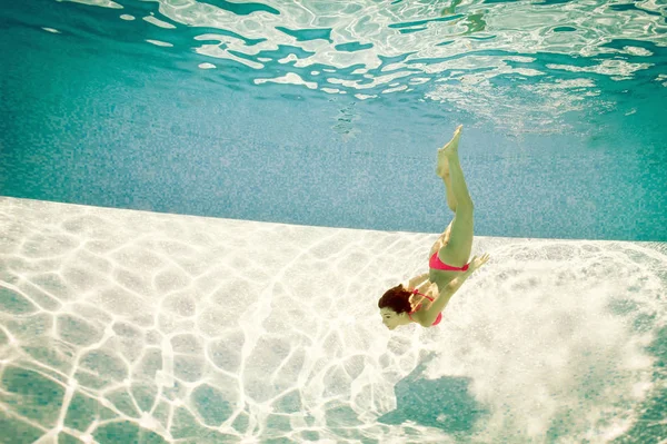 Girl portrait underwater with pink bikini in swimming pool.