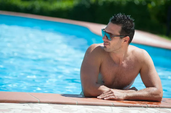 Portrait of a handsome man relaxing by swimming pool. — Stock Photo, Image