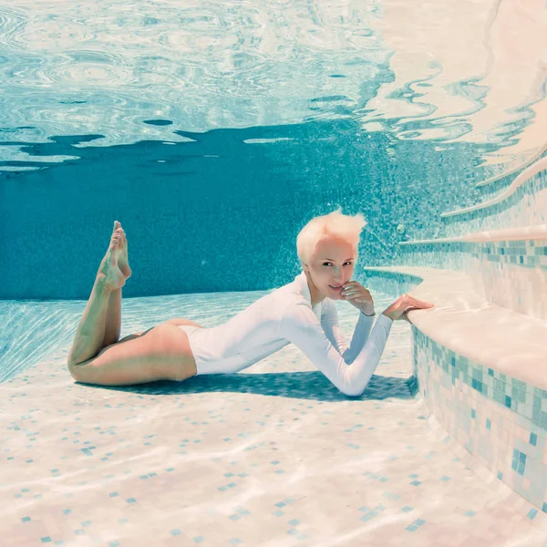 美丽的女人穿着白色泳衣水下在游泳池 — 图库照片