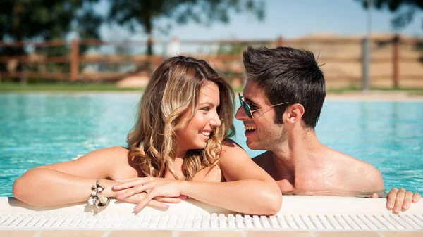 Portrait of a smiling young couple in a swimming pool. — Stock Photo, Image