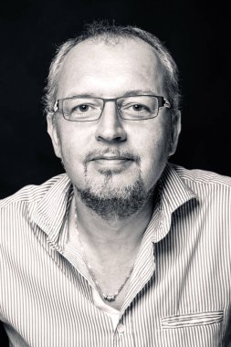 Orta yaşlı bir adam siyah arkaplanda yakın plan portresi yapıyor. Siyah ve beyaz resim. 