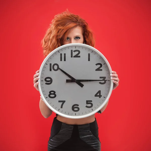 Joven Mujer Sosteniendo Reloj Oficina Contra Fondo Rojo —  Fotos de Stock