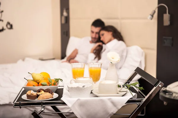 年轻夫妇在豪华旅馆房间里吃早餐 把重点放在盘子上 — 图库照片