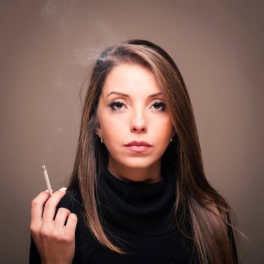 Kendine güvenen bir kadın sigara portresi içiyor. Koyu arka planda stüdyo moda fotoğraf. 