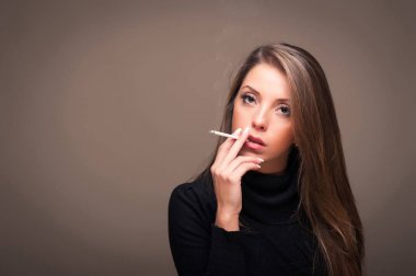 Sigara içen bir kadın portresi. Koyu arka planda stüdyo moda fotoğraf.
