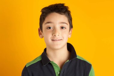 Turuncu arka planda gülümseyen çocuk portresi.