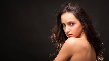 Young intimate brunette woman beauty portrait against dark background. 