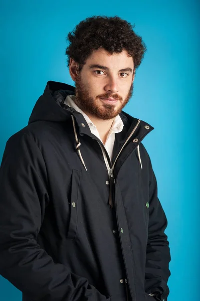 Portrait of confident young man wearing winter jacket against bl — Stock Photo, Image