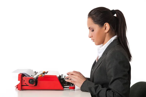 Joven secretaria atractiva escribiendo con una vieja máquina de escribir agains — Foto de Stock