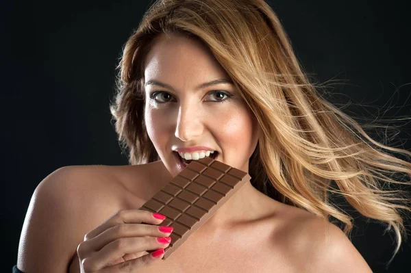 黒い背景にチョコレートバーを持つブロンドの女性 — ストック写真