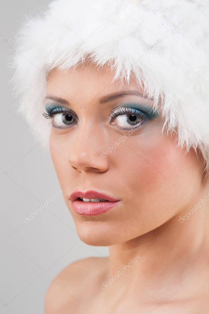 Beauty portrait of young woman with white bearskin. 