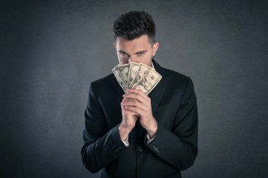 Grunge arka plan karşı gizli ifade ile dolar banknotlar arkasına saklanan Adam.