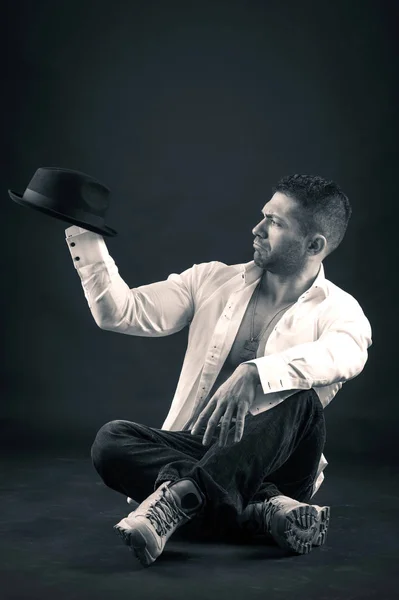 暗い背景に帽子をかぶって遊ぶ男の肖像画 白黒画像 — ストック写真