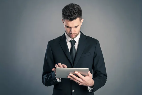 Jonge Zakenman Kijkt Naar Tablet Tegen Donkere Achtergrond — Stockfoto