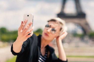 Mutlu genç kadın Paris'te cep telefonu ile selfie çekiyor, Fransa. Telefona odaklanın.